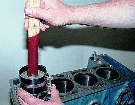 Легкими ударами деревянной ручки молотка по днищу поршня утапливаем его в цилиндр