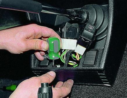 Отверткой по очереди поджимаем два фиксатора крепления нижней вставки 