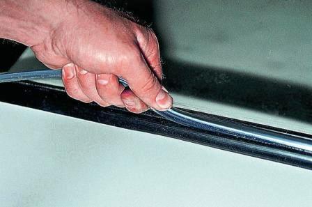 Переворачиваем стекло и движениями из стороны в сторону заправляем окантовку в уплотнитель