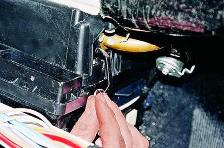 Поддеваем отверткой и поочередно снимаем четыре пружинные скобы крепления кожуха 