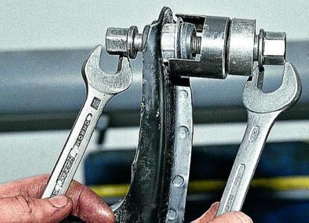 Затягиваем болт приспособления и последовательно выдавливаем шарниры из рычага в чашку приспособления