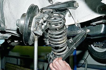 Убедившись, что витки пружины стянуты надежно, отжимаем нижний рычаг подвески вниз и вынимаем пружину 