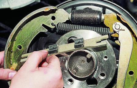 Отводим колодку в сторону, освобождая распорную планку, и снимаем планку