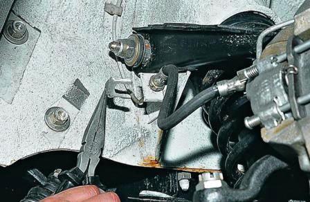 Пассатижами извлекаем скобу, фиксирующую тормозной шланг 