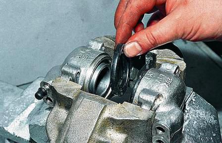 Поддев отверткой, снимаем защитные колпачки поршней